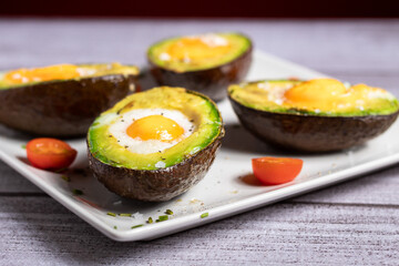 Primer plano de aguacate con huevo al horno encima de una tabla rústica gris elegante