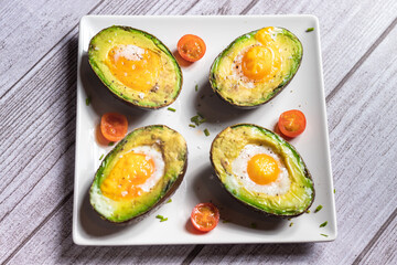 Aguacate con huevo al horno visto des de arriba encima de un fondo gris