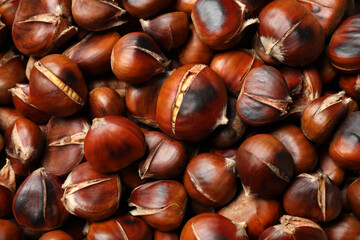 Pile of delicious edible roasted chestnuts as background, closeup
