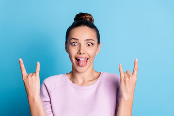 Photo of crazy hipster girl show horns symbol tongue out enjoy rejoice punk concert wear lilac pullover isolated over blue color background