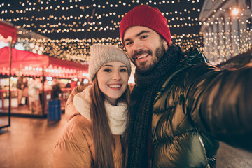 Photo of affectionate couple make selfie on street x-mas christmas town evening fair illumination...