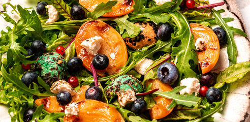 Easy recipe for summer salad with goat cheese, grilled apricots, arugula, berries, close-up