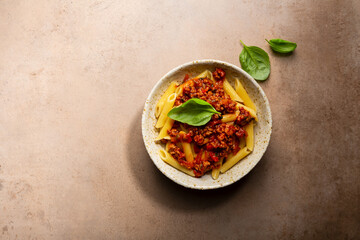 Overhead view of Pasta penne bolognese and basil leaves