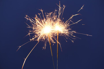 Bright burning sparkler on blue background, closeup