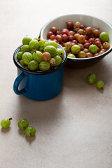 Close up of green gooseberry in blue enamel mug on stone table
