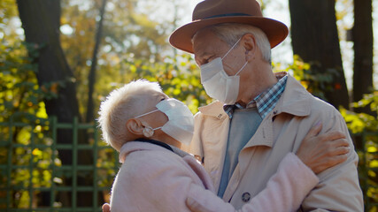 Portrait of senior couple wearing protective mask embracing in autumn park