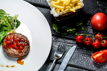 steak on a white plate with herbs on a black background
