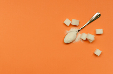 Fototapeta na wymiar Top view of teaspoon and sugar on the orange surface.Empty space