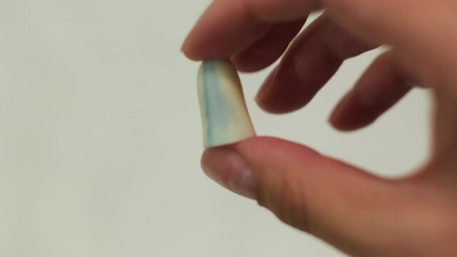 Close up of woman holding ear plugs in her fingers on white background. Concept. Pressing soft and soundproof earplugs in female young hands.
