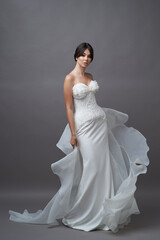 Beautiful bride in wedding dress posing on grey background