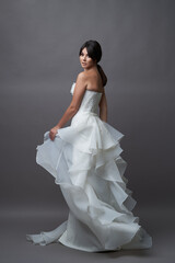 Fototapeta na wymiar Beautiful bride in wedding dress posing on grey background