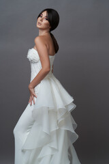 Beautiful bride in wedding dress posing on grey background