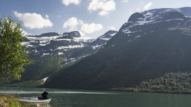 Boat Moored On The Lakeside At The Fjord During Winter With Rocky Mountain In The Background - motion time lapse
