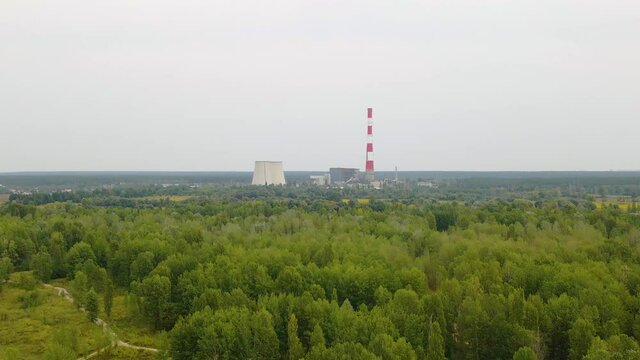Aerial view towards the TES 6 Coal-fired power factory, over green forest, dark, overcast day, in Kiev, Ukraine - dolly, drone shot