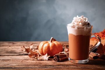 Delicious pumpkin latte and cinnamon on wooden table. Space for text