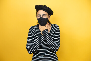 Young beautiful brunette woman wearing french beret and glasses over yellow background with mask touching painful neck, sore throat for flu, clod and infection