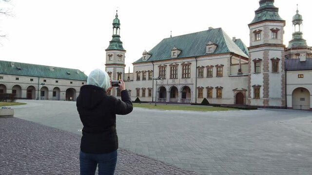 A steady shot of Girl tourist makes a photos of old king palace in the square