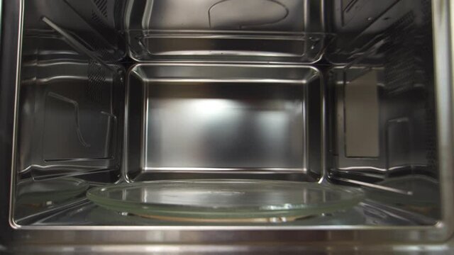 View inside of microwave oven, concept of cooking and technologies. Household utensils. Close up of empty microwave turntable glass tray inside of the microwave oven.