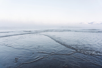 the water freezes and covers the sand with ice and snow on the seashore during the winter frost