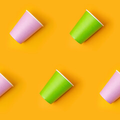 Pattern from green and pink paper drinking cups arranged diagonally on yellow background. Birthday party celebration abstract fashion baby shower concept. Minimalist style