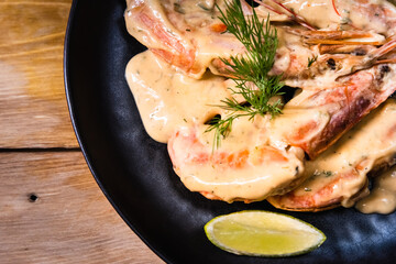 Delicious fried langoustines in sauce on a black plate, prepared in an Asian style. Fast and ready meal concept