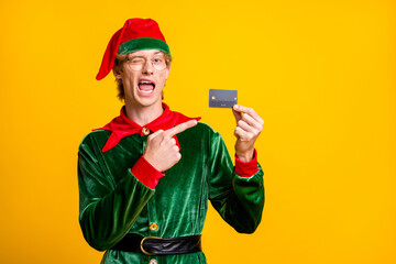 Photo of guy hold credit card direct finger blink eye wear elf velvet green costume hat glasses...