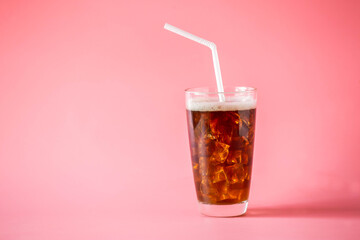 A glass of cold black coffee with white straw on pink background. Low sugar beverage for healthy