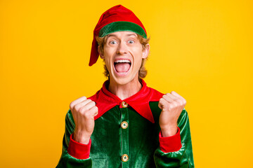 Photo of young mad guy raise fists open mouth wear elf velvet green costume headwear isolated...