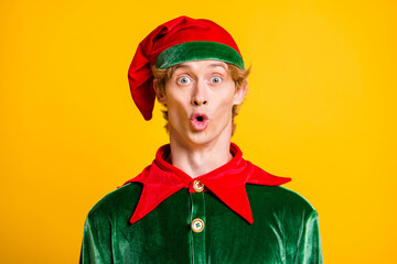 Photo of young guy look camera shocked expression wear elf velvet green costume cap isolated yellow color background