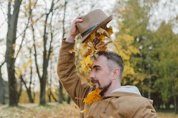 A man in a hat on an autumn day against a background of beautiful leaves.