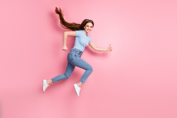 Fototapeta na wymiar Photo portrait of running jumping up girl showing thumbs up isolated on pastel pink colored background