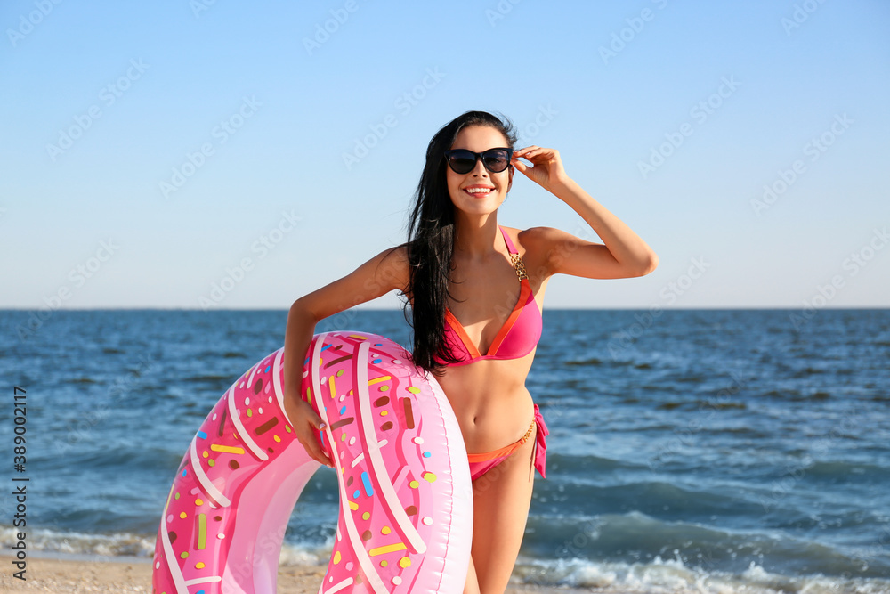 Sticker beautiful young woman in pink stylish bikini with inflatable ring on beach