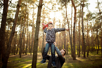 Playful. Father and son walking and having fun in autumn forest, look happy and sincere. Laughting, playing, having good time together. Concept of family, happiness, holidays, childhood, lifestyle.