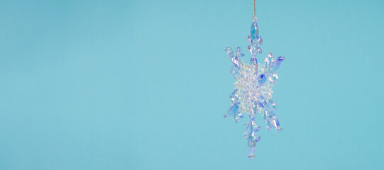 Hanging Winter snowflake, side view, close-up on a blue monochrome background. Selective focus, copy space, banner