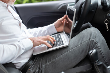 Businessman using his laptop in car