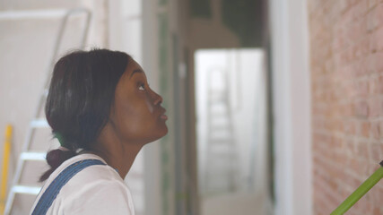 Young african woman decorating wall doing house renovation