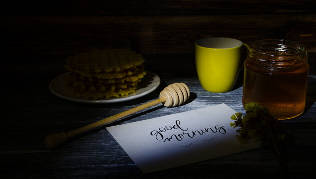 Still life with cup of coffee and waffles on the wooden background. Photo taken in low light key.