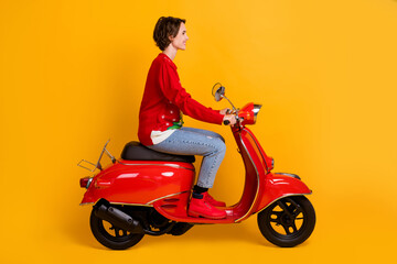 Obraz na płótnie Canvas Full length profile side photo of positive girl ride red scooter travel x-mas time eve noel party wear christmas tree decor pullover denim jeans isolated bright shine color background