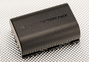 Eine schwarze Lithium-Batterie (Li-ion Battery / Akku) liegt auf einem metallischen Untergrund
