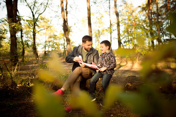 Warm. Father and son walking and having fun in autumn forest, look happy and sincere. Laughting, playing, having good time together. Concept of family, happiness, holidays, childhood, lifestyle.