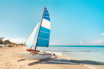 sailing catamaran is parked on the white sand on the seashore against the backdrop of beautiful tropical nature. tourist attractions in Cuba. - obrazy, fototapety, plakaty