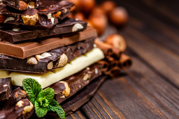 Stack of chocolate slices with mint leaf on a wooden table.Assortment of fine chocolates in white, dark, and milk chocolate. Sweet food photo concept.