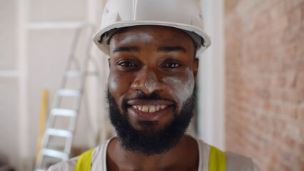 Portrait of professional african worker with dirty posing in protective uniform and helmet