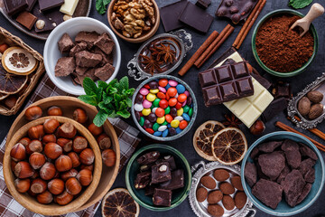 Assortment of fine chocolates in white, dark, and milk chocolate. Broken chocolate pieces. Sweet food photo concept. Top view with copy space