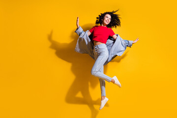 Fototapeta na wymiar Full length photo of cute lady look empty space jump wear striped jeans cropped red t-shirt jacket sneakers isolated yellow color background