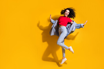 Fototapeta na wymiar Full length photo of girl jump palms wear striped jeans cropped red t-shirt jacket sneakers isolated yellow color background