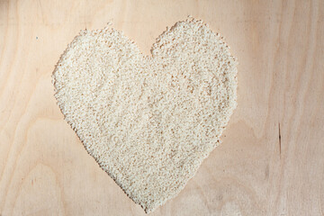 Rice heart on wooden background with place for an inscription. Heart symbol made from rice. Heart made of cereals. Healthy eating