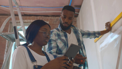 Young african couple doing house renovation consulting internet on tablet pc