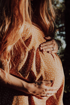 Pregnant woman holding hands protectively over belly.Pregnant woman feeling happy while taking care of her child. The young expecting mother hugs baby in pregnant belly. Maternity prenatal care.