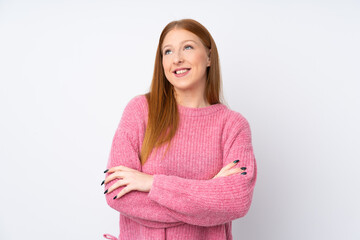 Obraz premium Young redhead woman with pink sweater over isolated white background looking up while smiling